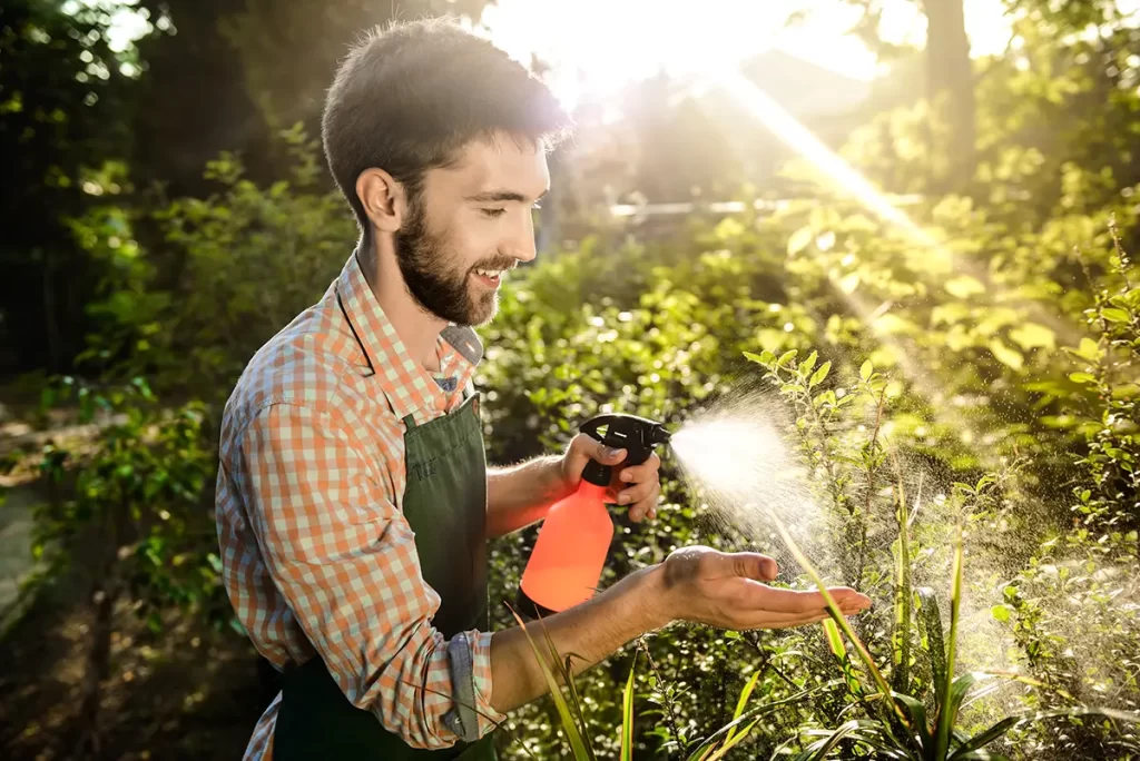 A professional Fixxway landscaper inspecting a smart irrigation system controller while tending to garden plants in Tampa, Florida.