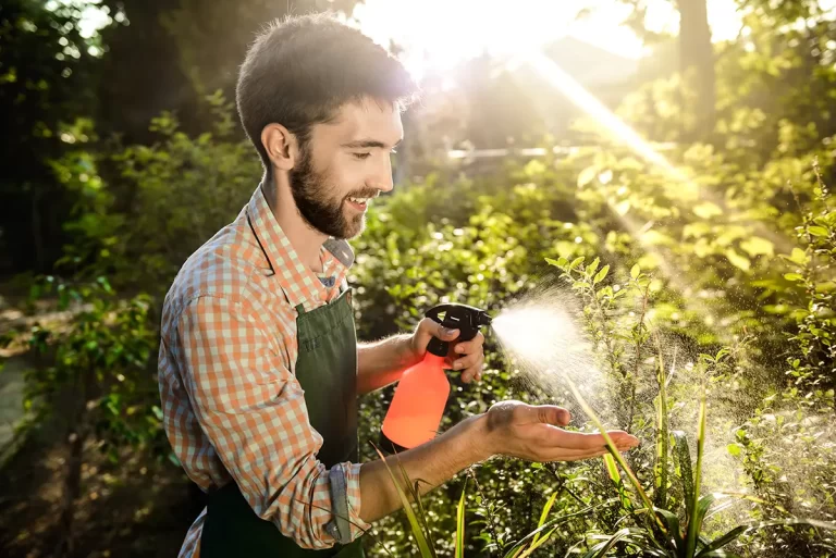 A professional Fixxway landscaper inspecting a smart irrigation system controller while tending to garden plants in Tampa, Florida.